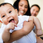 affectionate couple hugging baby at home
