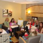 friends gathered in living room with newborn baby