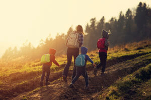 Mother and little kids hiking in the mountains at golden hour in the sunset