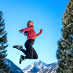 woman in workout clothes jumping in snowy woods