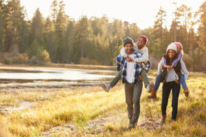 Parents Giving Children Piggyback Ride On Walk By Lake - how nature can provide stress relief