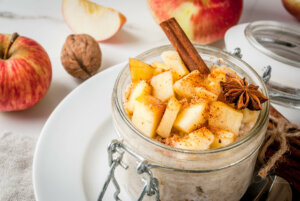 Apple pie overnight oats, with apples, yogurt, cinnamon, spices, walnuts. In a glass, on a white marble table - healthy breakfast ideas for fall