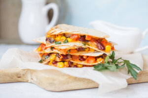 Vegetarian quesadilla with vegetables and cheese on a wooden board, light background - healthy breakfast ideas for fall