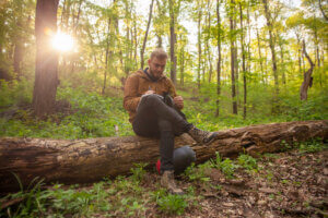 one young man, in forest, holding a flower in his hands, writing down his notes on it - How Nature Can Provide Stress Relief