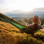 Woman hiker resting after climbing in a hammock at sunset - How Nature Can Provide Stress Relief featured image