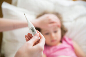 Close-up thermometer. Mother measuring temperature of her ill kid - comparing rsv the flu and covid