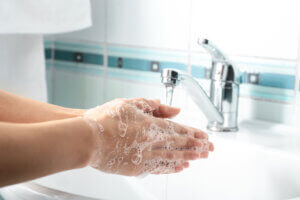 Woman washing hands in sink comparing rsv covid and flu symptoms