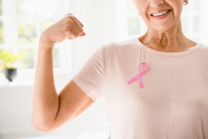 Mature senior elderly strong woman in pink t-shirt with pink ribbon supporting fighting for breast cancer movement. Togetherness, oncology recovery conceptMature senior elderly strong woman in pink t-shirt with pink ribbon supporting fighting for breast cancer movement. celebrating breast cancer awareness month