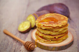 Sweet potato pancakes with honey on wooden plate - healthy winter breakfast ideas