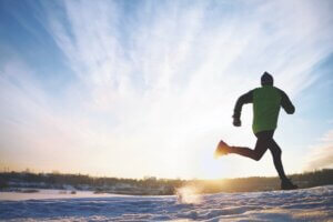 Back view of energetic sportsman running in winter