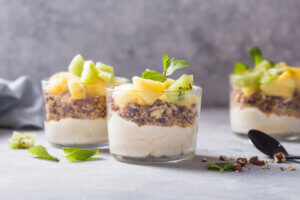 Homemade yogurt parfait with granola, kiwi fruit, pineapple and nuts in a glass for healthy breakfast on concrete background healthy winter breakfast ideas