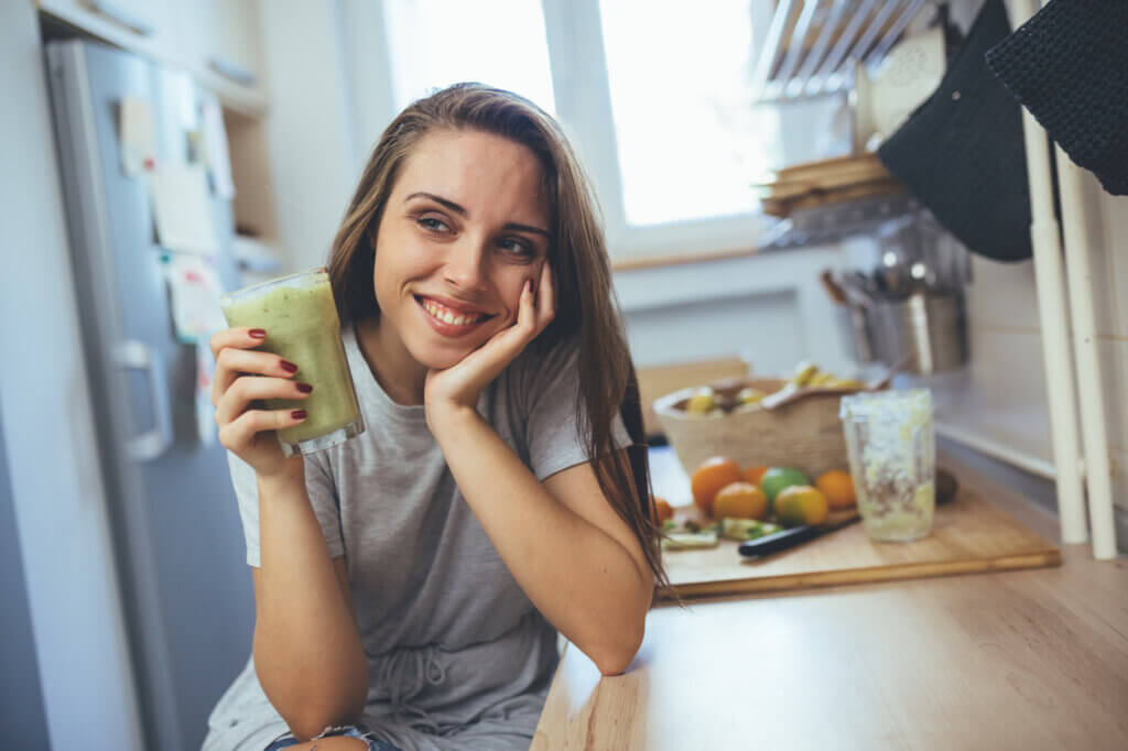 woman drinking smoothie in kitchen how a dietitian can help you meet health goals