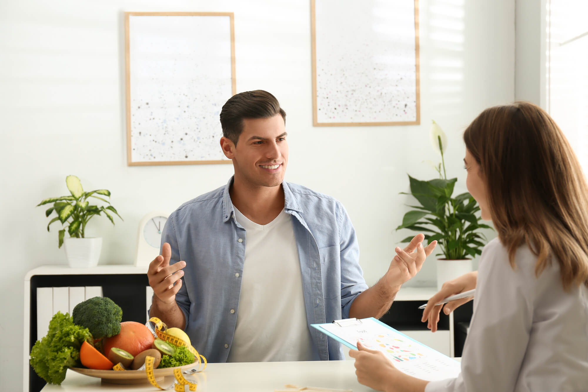 Young nutritionist consulting patient at table in clinic