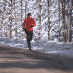 happy motivated smiling sporty 45 years old endurance sport athlete woman running jogging along asphalt road on cold sunny winters day with snow and snowcovered trees following heartfelt advice