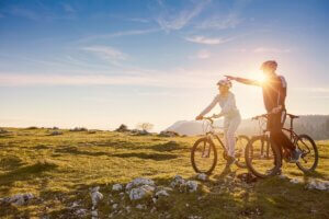 Biker couple with mountain bike pointing in distance at countryside.