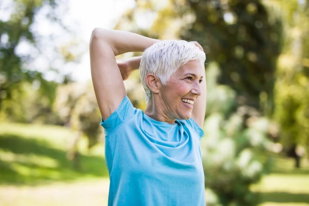 Portrait of senior woman doing exercise for stretching arms in the park caring for women’s hormones