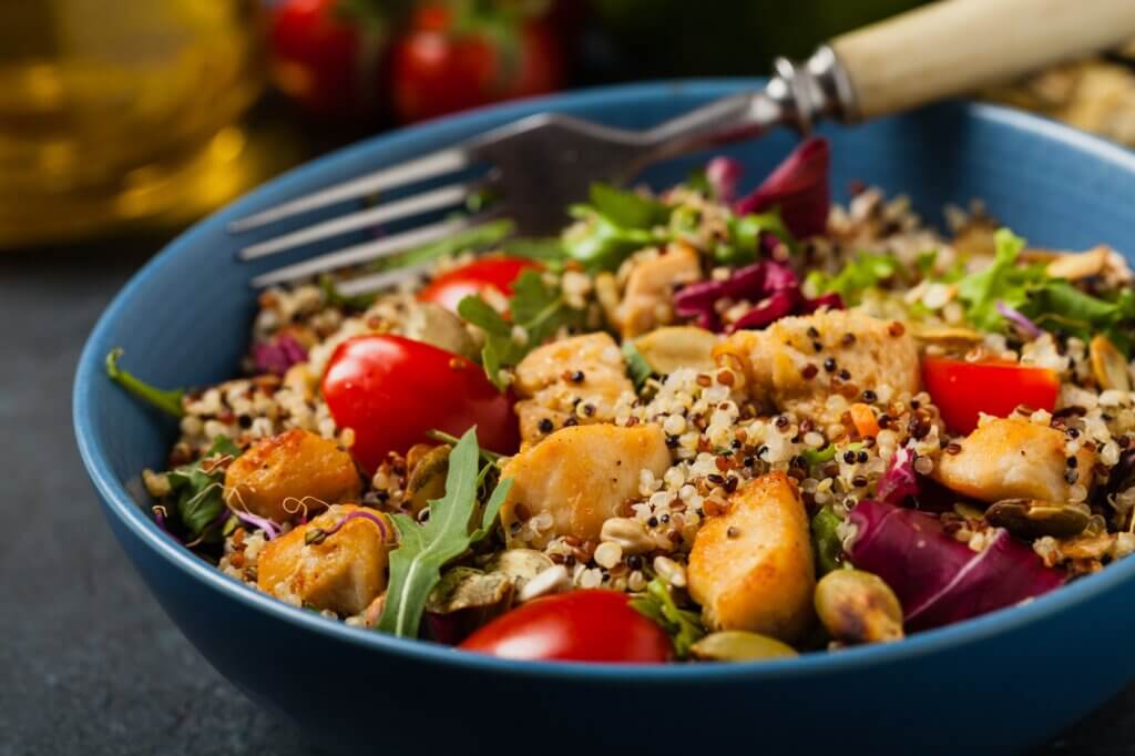 Salad with quinoa, avocado and chicken. Front view. Served in a blue bowl. healthy meals holiday leftovers
